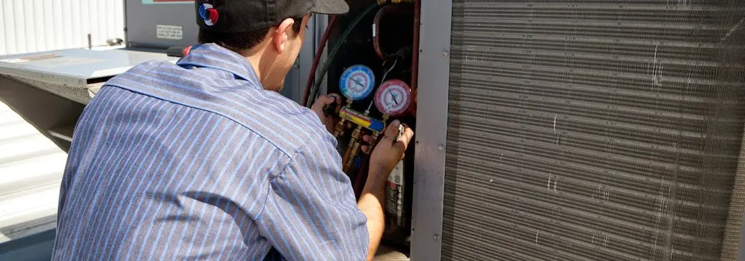 HVAC technician servicing a condenser unit in New Prague